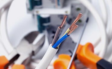 Stripped electrical wires with tools in the background.